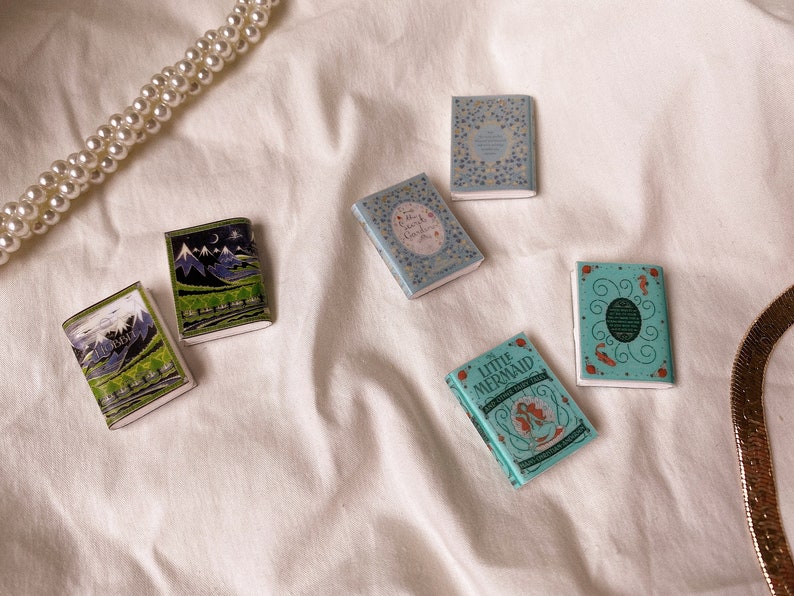 Three pairs of miniature books laid out flat to show the covers. These are all green in colour. The hobbit. The secret garden. The little mermaid.