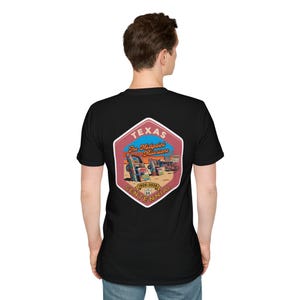 Puede incluir: Camiseta negra con un gráfico colorido de coches antiguos y una señal de tráfico. El gráfico incluye el texto "Texas The Midpoint Milestone 1926-2026 Centennial" en un diseño hexagonal. La camiseta está hecha de un material suave.