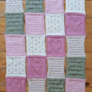 May include: A knitted blanket with a variety of patterns in pink, green, and white. The blanket is made up of squares with different heart designs.