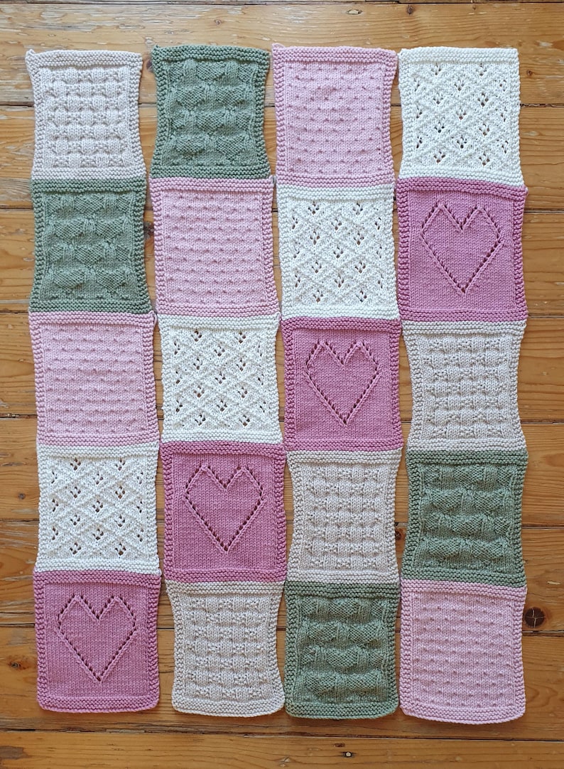 May include: A knitted blanket with a variety of patterns in pink, green, and white. The blanket is made up of squares with different heart designs.