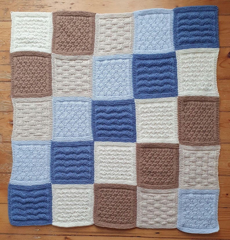 May include: A knitted baby blanket with a patchwork design. The blanket is made up of squares in shades of blue, brown, and white.