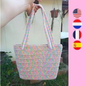 May include: A pastel-colored crocheted tote bag with white straps. The bag is made with a variety of colors, including pink, blue, green, and yellow.