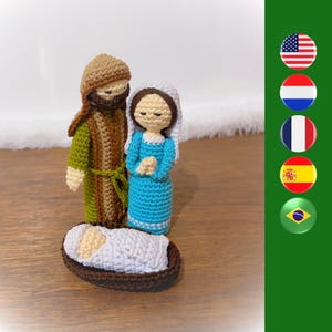 May include: Crocheted nativity scene with a brown-haired Joseph, a blue-haired Mary, and a baby Jesus in a brown basket.