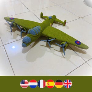 May include: A green crocheted model of a vintage bomber airplane with red, white, and blue roundels on the wings and fuselage. The airplane has four propellers and a detailed cockpit.