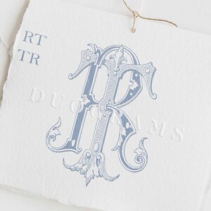 May include: A blue and white monogram with the letters "RT" in a decorative font. The monogram is on a white background with the text "DUOGRAMS" below it.
