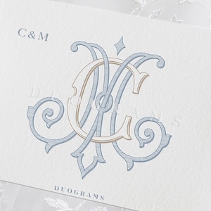 May include: A white card featuring a blue and beige intertwined monogram of the letters C and M. The text C&M appears in the top left corner, while the word DUOGRAMS is printed in a serif font at the bottom center of the textured paper surface.