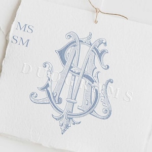 May include: A blue and white monogram with the letters "MS" intertwined. The monogram is surrounded by decorative flourishes. The text "DUOGRAMS" is printed below the monogram.