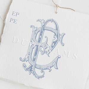 Peut inclure: Un monogramme bleu et blanc avec les lettres "EP" dans une police décorative. Le monogramme est entouré d'un motif floral. Le texte "DUOGRAMS" est imprimé sous le monogramme.