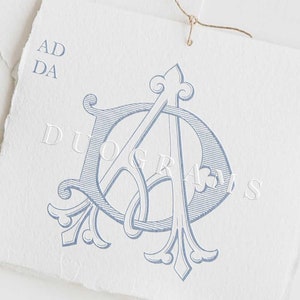 May include: A blue and white monogram design featuring the letters "AD" intertwined. The letters are in a decorative font and are surrounded by ornate flourishes. The text "DUOGRAMS" is also visible in the image.
