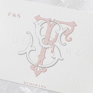 May include: A white rectangular card featuring a decorative monogram of the letters F and S in muted pink and grey. The text F&S appears in the top left corner, and the word DUOGRAMS is printed in a serif font at the bottom center of the card.