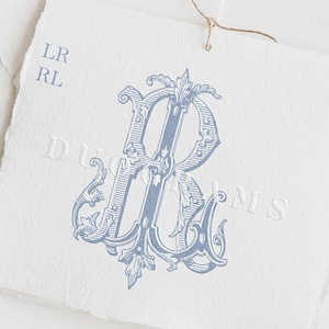 Puede incluir: Un monograma azul y blanco con la letra "R" en una fuente decorativa y adornada. El monograma está sobre un fondo blanco con el texto "DUOGRAMS" debajo.