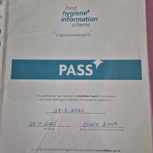 May include: A food hygiene information scheme certificate from Midlothian, Scotland, with the text "CHOCOMANGO" and the word "PASS" in large letters. The certificate is dated March 28, 2025, and signed by Clare Boos.