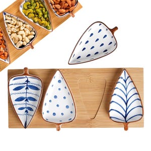 May include: A collection of leaf-shaped serving dishes and trays. The dishes are white with blue patterns and brown rims. The trays are made of bamboo. The dishes are designed to hold snacks or appetizers.