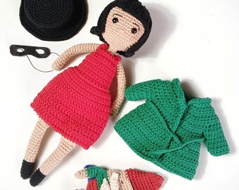 May include: A selection of handmade crochet dolls and accessories. The main doll is in a red dress and has black hair. There is a black hat, a green coat, a black mask, and a gnome doll. The items are displayed on a white surface.