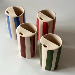 May include: A set of three ceramic mugs with a speckled, matte finish. The mugs are in shades of cream, light gray, and dark gray. Each mug has a simple, minimalist design, perfect for coffee or tea.
