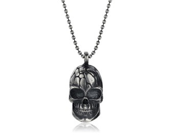 May include: A silver chain necklace with a detailed skull pendant. The skull has a textured surface and a toothy grin.