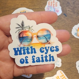 May include: White sticker with a blue sky, palm trees, and sunglasses with the text "With eyes of faith".