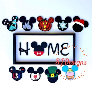 May include: A black wooden sign with the word "HOME" in white letters. The "O" is replaced with a black Mickey Mouse head with red ears and a red nose. There are 10 Mickey Mouse heads with different designs around the sign, including a pumpkin, a snowflake, a Santa hat, a birthday cake, a castle, a USA flag, a heart, a shamrock, and an Easter egg.