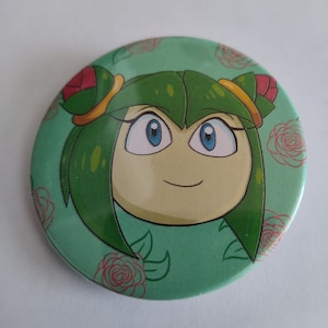 May include: A green and yellow character with blue eyes and a smile on a green background with pink roses. The character has green hair and a yellow headband.