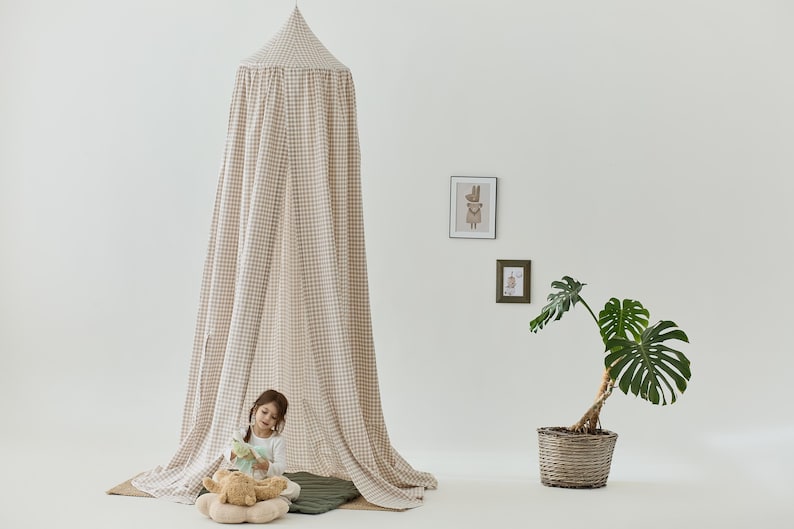 Pu&ograve; includere: Una tenda a baldacchino a quadri bianchi e marroni con un bambino seduto all'interno. La tenda &egrave; realizzata in un tessuto morbido e leggero, ideale per creare uno spazio accogliente e privato per un bambino per giocare o rilassarsi.