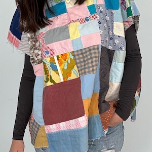 May include: A patchwork shirt featuring a mix of colours and patterns, including floral, plaid and geometric designs. The shirt has a button-up collar and short sleeves.