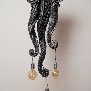 May include: A black metal octopus-shaped ceiling light fixture with three hanging light bulbs.
