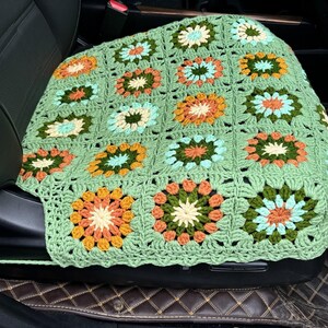 Pu&ograve; includere: Coprisedile per auto in crochet verde con un motivo floreale in tonalit&agrave; arancio, giallo, verde e blu.