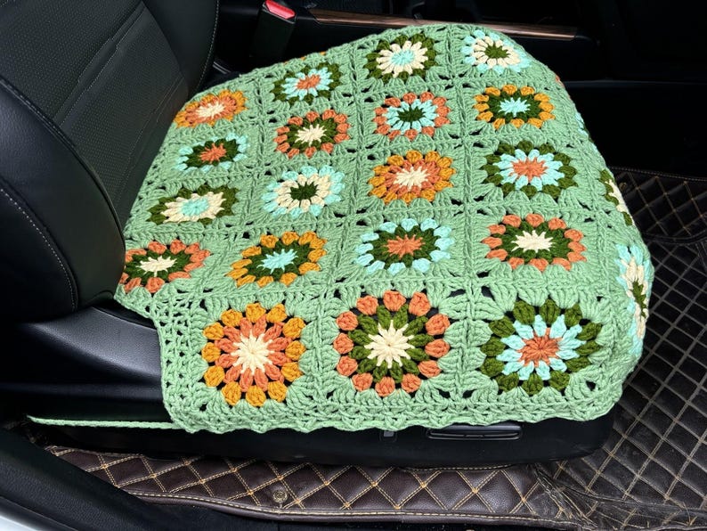 Pu&ograve; includere: Coprisedile per auto in crochet verde con un motivo floreale in tonalit&agrave; arancio, giallo, verde e blu.