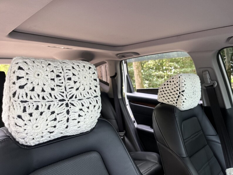 May include: Two white crocheted headrest covers for car seats. The covers are made with a square pattern and have a delicate, lacy look.