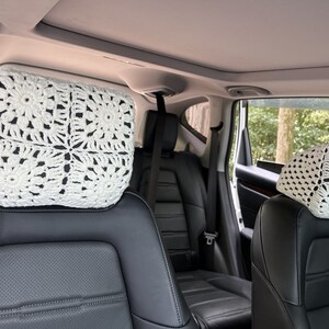 May include: Two white crocheted headrest covers for car seats. The covers are made with a delicate, lacy pattern.