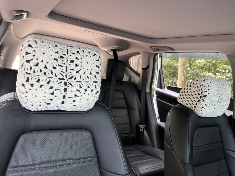 May include: Two white crocheted headrest covers for car seats. The covers are made with a delicate, lacy pattern.