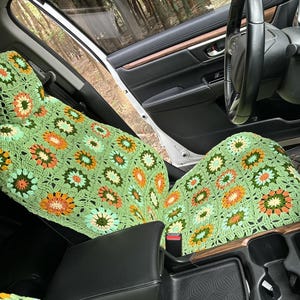 Pu&ograve; includere: Coprisedili per auto in crochet verde, arancione e bianco con un motivo floreale.