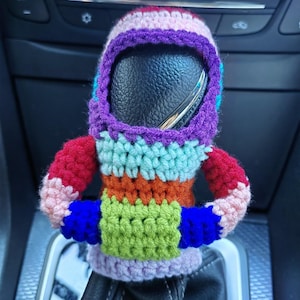 May include: A colourful crocheted car gear shift cover with a rainbow pattern. The cover is made of different coloured yarn and has a blue and green stripe on the bottom.