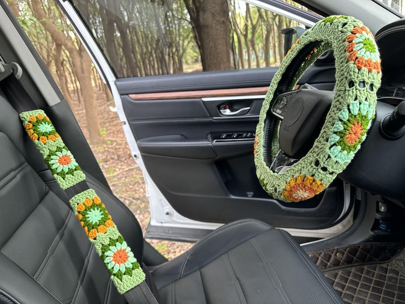 Pu&ograve; includere: Un coprivolante e un copri cintura di sicurezza abbinati, all'uncinetto in verde, giallo e arancione. Le coperture presentano un motivo floreale.