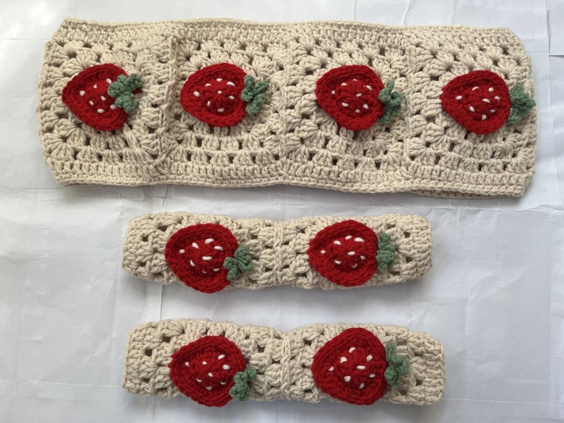 May include: Three crocheted headbands with strawberry designs. The headbands are beige with red and green strawberries.
