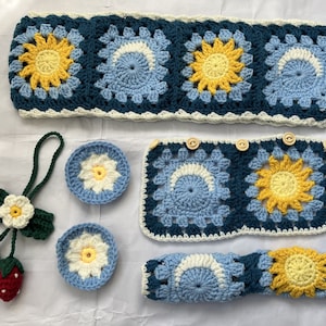 May include: A set of crocheted items in blue, white, and yellow. The set includes a headband, a pair of coasters, and a long crocheted piece. The crocheted pieces feature a flower design.