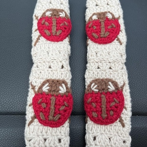 May include: Two crocheted beige doorstop covers with red and brown ladybug designs.