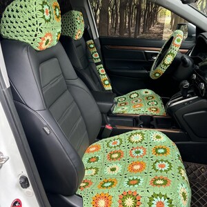 Pu&ograve; includere: Coprisedili per auto in crochet verde con motivi floreali. Le copertine includono una copertura per il poggiatesta e una copertura per il cuscino del sedile. Le copertine sono all'interno di un'auto con un sedile in pelle nera.