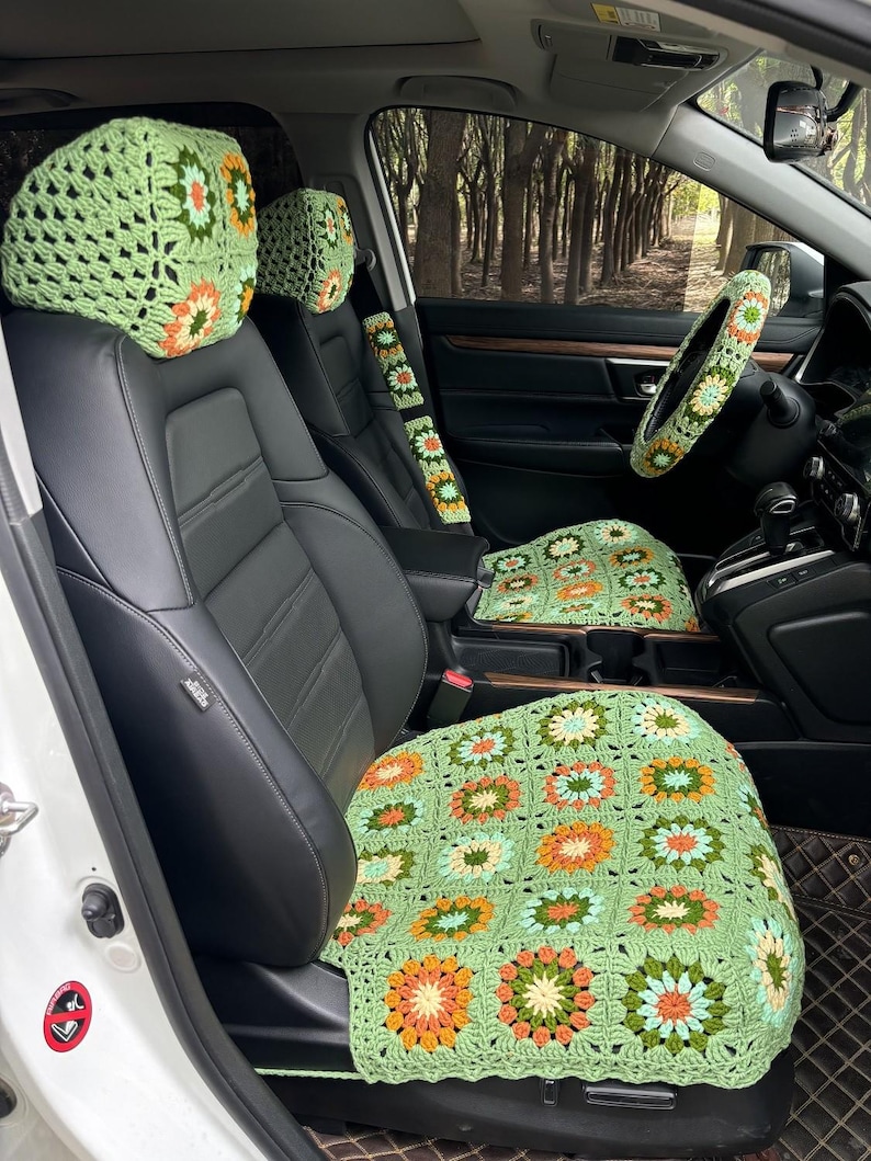 Pu&ograve; includere: Coprisedili per auto in crochet verde con motivi floreali. Le copertine includono una copertura per il poggiatesta e una copertura per il cuscino del sedile. Le copertine sono all'interno di un'auto con un sedile in pelle nera.