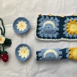 May include: A set of crocheted items in blue, yellow, and white. The set includes a coaster, a headband, and a small flower-shaped keychain.