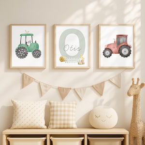 Puede incluir: Tres impresiones enmarcadas en acuarela con ilustraciones de temática agrícola. Una muestra un tractor verde, otra un tractor rojo, y la tercera muestra el nombre "Otis" con una gran "O". Las impresiones están en marcos de madera clara, adecuados para una habitación infantil.