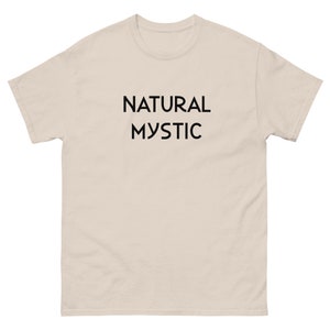 K&ouml;nnte beinhalten: Hellbeige T-Shirt mit dem schwarzen Aufdruck "NATURAL MYSTIC" mittig auf der Vorderseite. Das T-Shirt hat kurze &Auml;rmel und einen Rundhalsausschnitt.