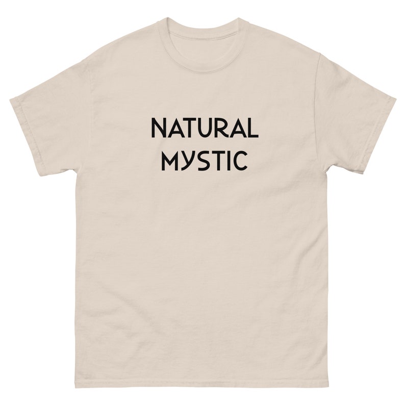 K&ouml;nnte beinhalten: Hellbeige T-Shirt mit dem schwarzen Aufdruck "NATURAL MYSTIC" mittig auf der Vorderseite. Das T-Shirt hat kurze &Auml;rmel und einen Rundhalsausschnitt.