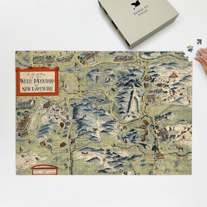 May include: A completed jigsaw puzzle depicting a vintage map of the White Mountains of New Hampshire. The puzzle features a detailed illustration with a variety of colors, including green, blue, and brown. The puzzle is partially assembled, with a few pieces remaining to be placed. The puzzle box is visible.