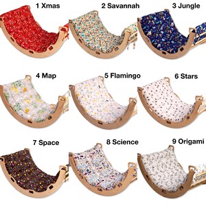 May include: Nine wooden rocking cradles with different fabric covers. The covers feature various patterns, including Christmas, Savannah, jungle, map, flamingo, stars, space, science, and origami.