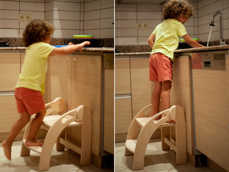 May include: Two children stand on wooden step stools in a kitchen. The step stools are made of natural wood and have two steps. The children are wearing casual clothing.