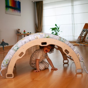 Wooden climbing arch with cozy pillow, great for baby nursery decor.