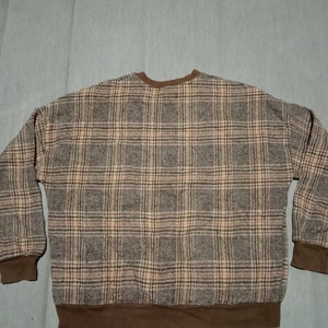 May include: A brown and beige plaid sweater with a brown ribbed collar and cuffs.