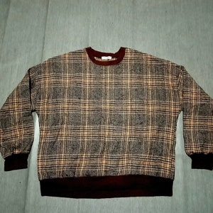 May include: A brown, beige, and black plaid sweater with a maroon ribbed collar and cuffs.