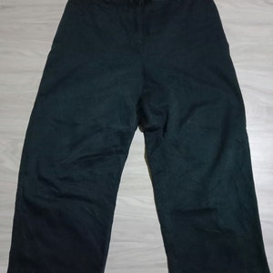 May include: Dark green wide-leg pants with a straight leg and a waistband with a button and zipper closure.